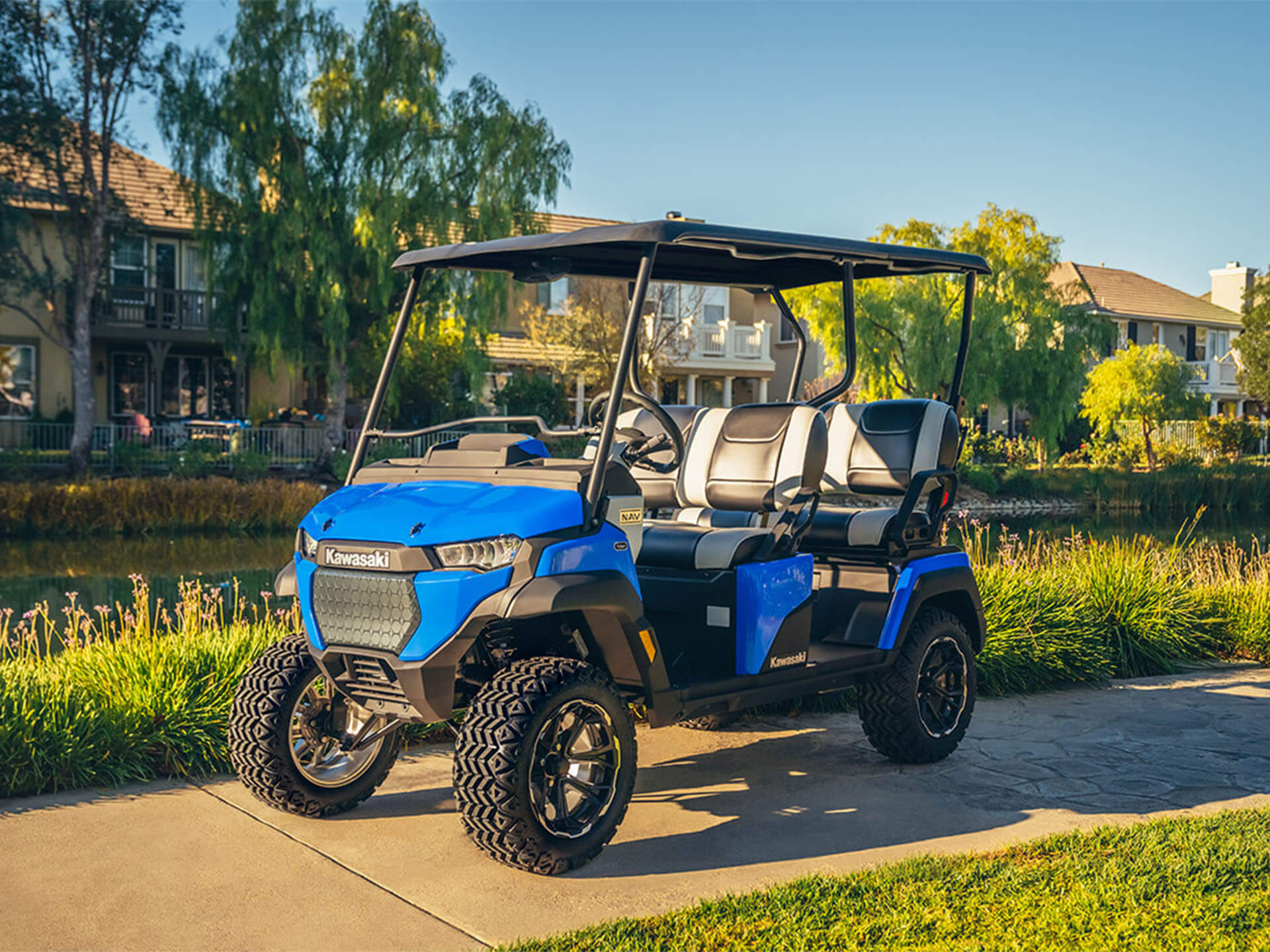 02 Best Golf Cart 2026 Kawasaki NAV 4e Blue 2026 Kawasaki NAV 4e lifted golf cart parked on a lakeside neighborhood path