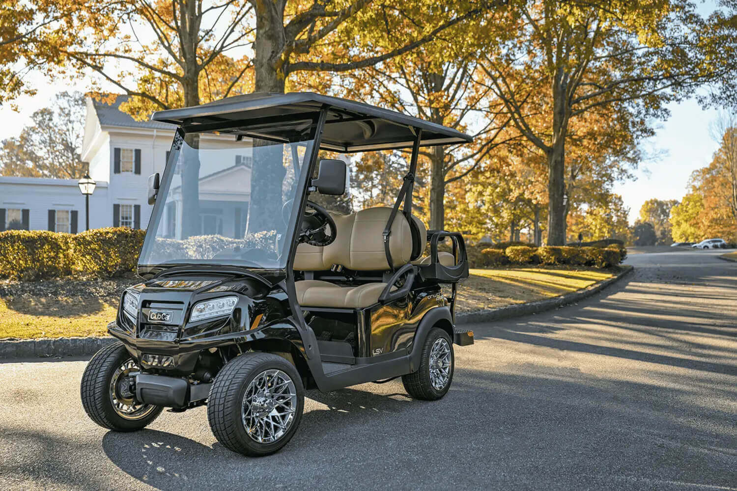 05 Best Golf Cart 2026 Club Car Onward Lithium Black 2026 Club Car Onward golf cart with premium tan seats parked on a tree-lined autumn street