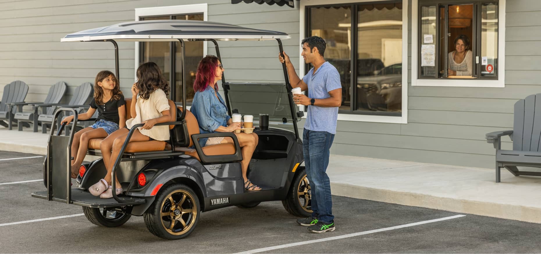 06 Best Golf Cart 2026 Yamaha Drive-2 Family gathered around a 2026 Yamaha Drive-2 PTV golf cart outside a coffee shop