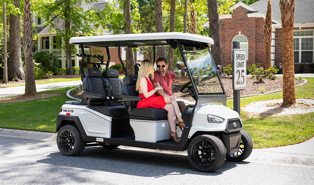 07 Best Golf Carts 2026 Bintelli Nexus Gen2 Couple riding a white 2026 Bintelli Nexus Gen2 4 seater street legal golf cart past palm trees