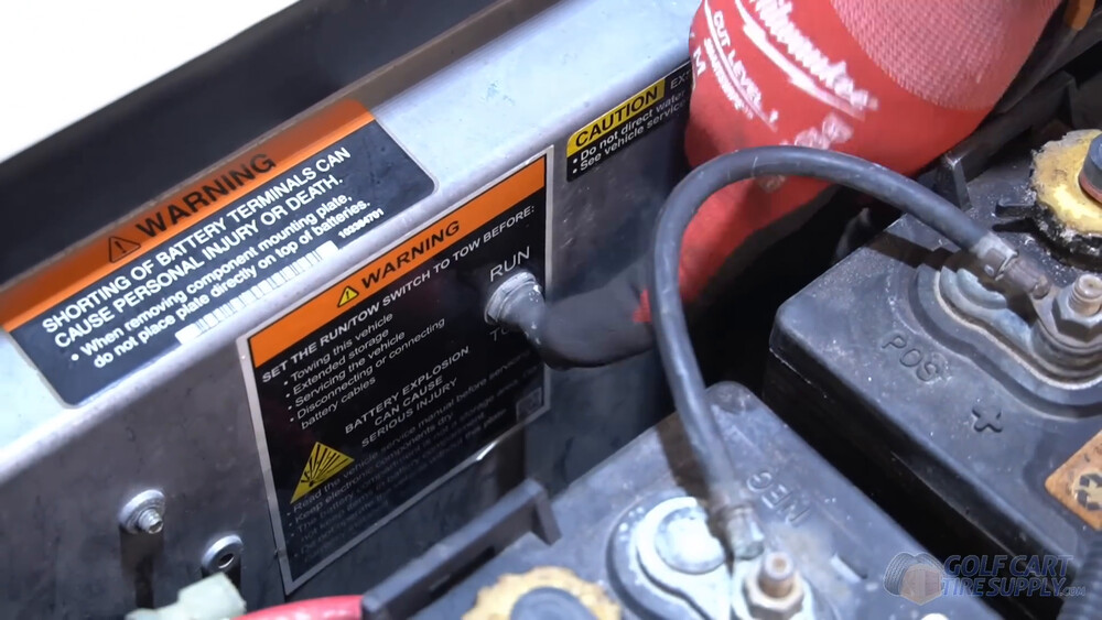 Run/Tow switch on a Club Car Tempo Run and Tow switch with warning labels on the silver panel inside the battery bay of a 2019 Club Car Tempo golf cart