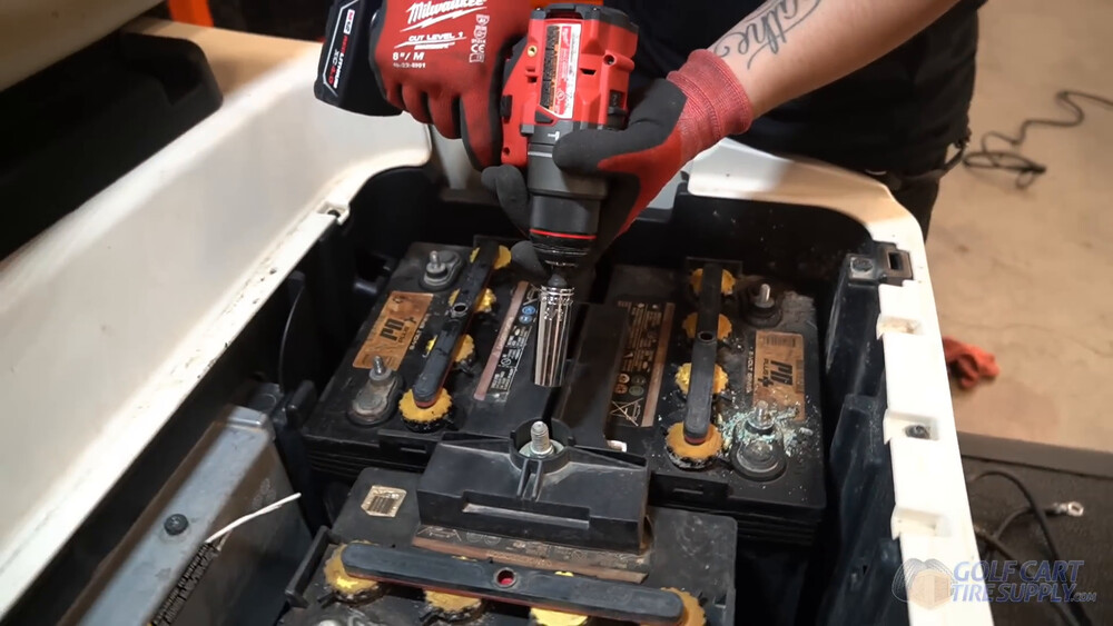 Removing Club Car Tempo battery hold-downs Cordless driver with a 5/8 inch deep socket loosening a battery hold-down in a white 2019 Club Car Tempo golf cart