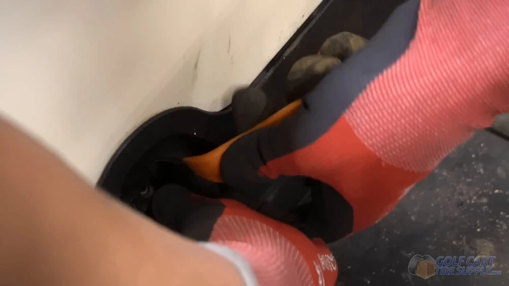 Popping the Club Car Tempo charge port trim ring Orange plastic trim tool prying off the charge receptacle trim ring on a white 2019 Club Car Tempo golf cart