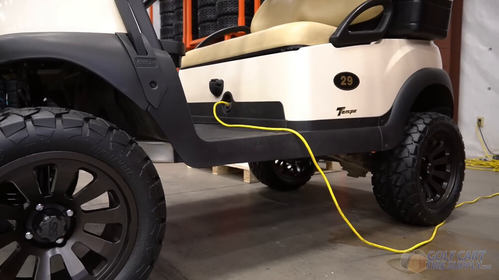 Charging a Club Car Tempo with an extension cord Yellow extension cord plugged into the front charge port of a white 2019 Club Car Tempo golf cart numbered 29