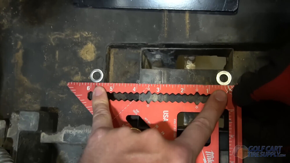Marking bracket holes in a Club Car Tempo battery tray Speed square and washers marking bracket bolt holes in the battery tray of a 2019 Club Car Tempo golf cart