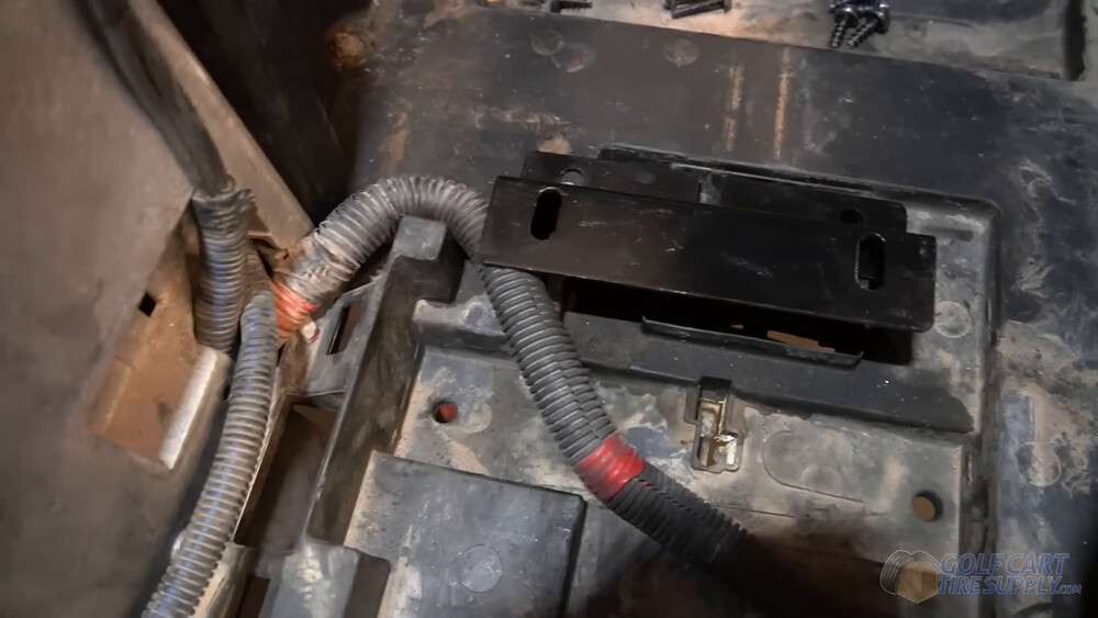 Tucking the Club Car Tempo harness under the bracket Main wiring harness tucked under a bolted down battery bracket in the tray of a 2019 Club Car Tempo golf cart