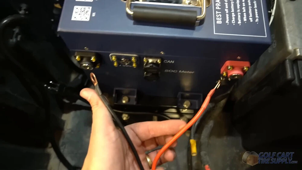New battery leads in a Club Car Tempo Hand holding the new black and red battery leads in front of the ALLIED lithium battery in a 2019 Club Car Tempo golf cart