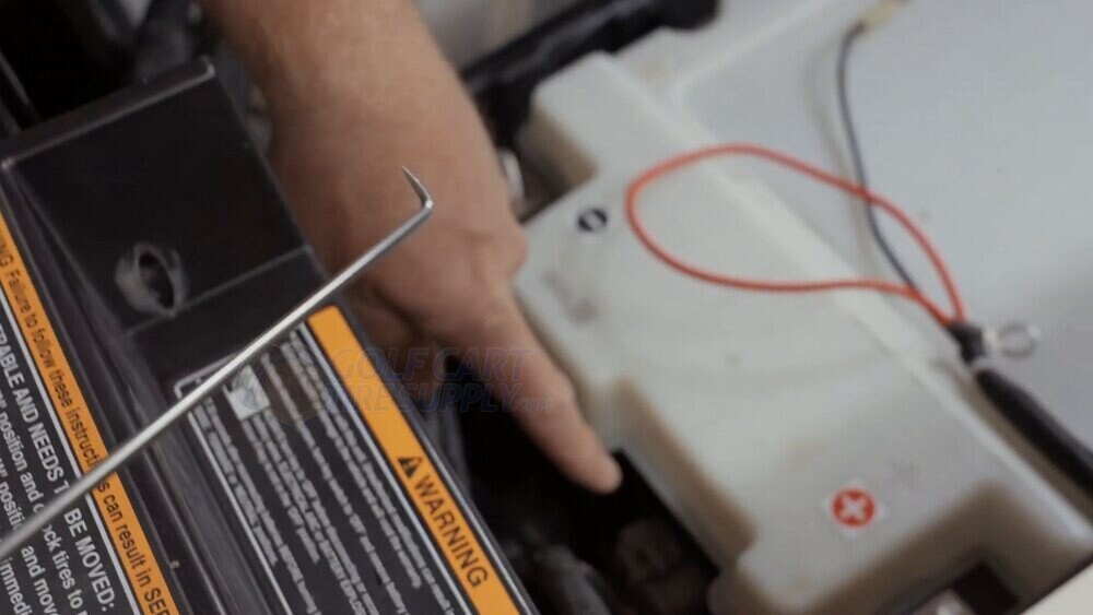 Using a pick to release the battery communication plug on an EZGO RXV ELiTE Gen 2 Hands using a small pick to release the battery communication plug on a Gen 2 EZGO RXV ELiTE