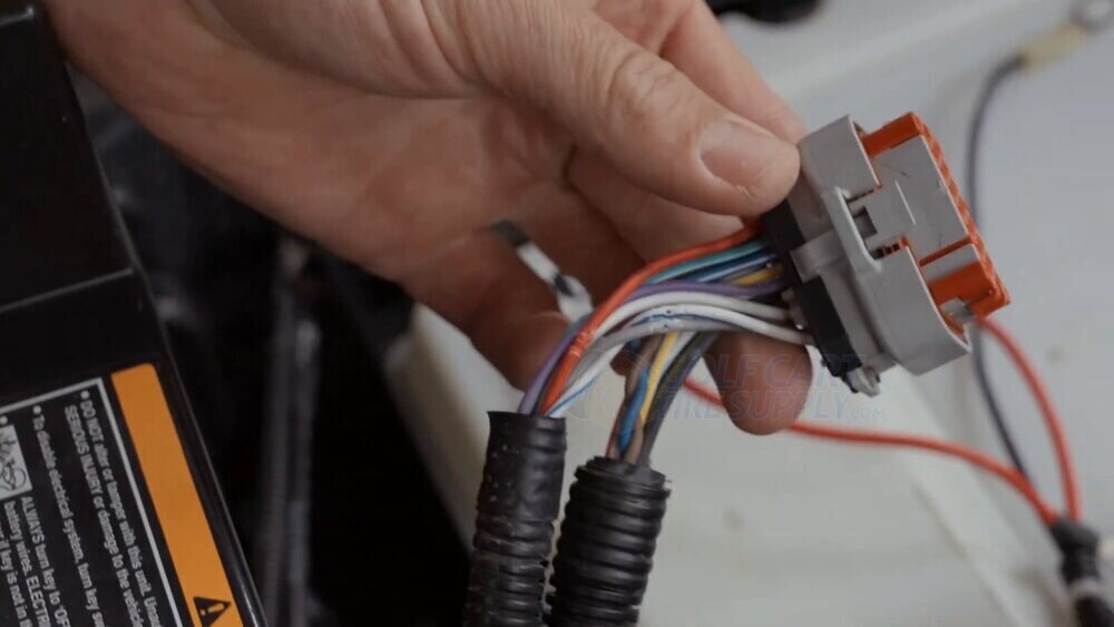 Battery communication plug unclipped and in hand on an EZGO RXV ELiTE Gen 2 The battery communication plug unclipped and held in hand on a Gen 2 EZGO RXV ELiTE