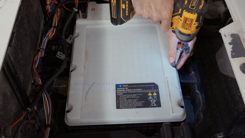 Removing the hold-down hardware and lifting the white Samsung pack from an EZGO RXV Backing out the hold-down hardware on the white Samsung factory lithium battery in a Gen 2 EZGO RXV